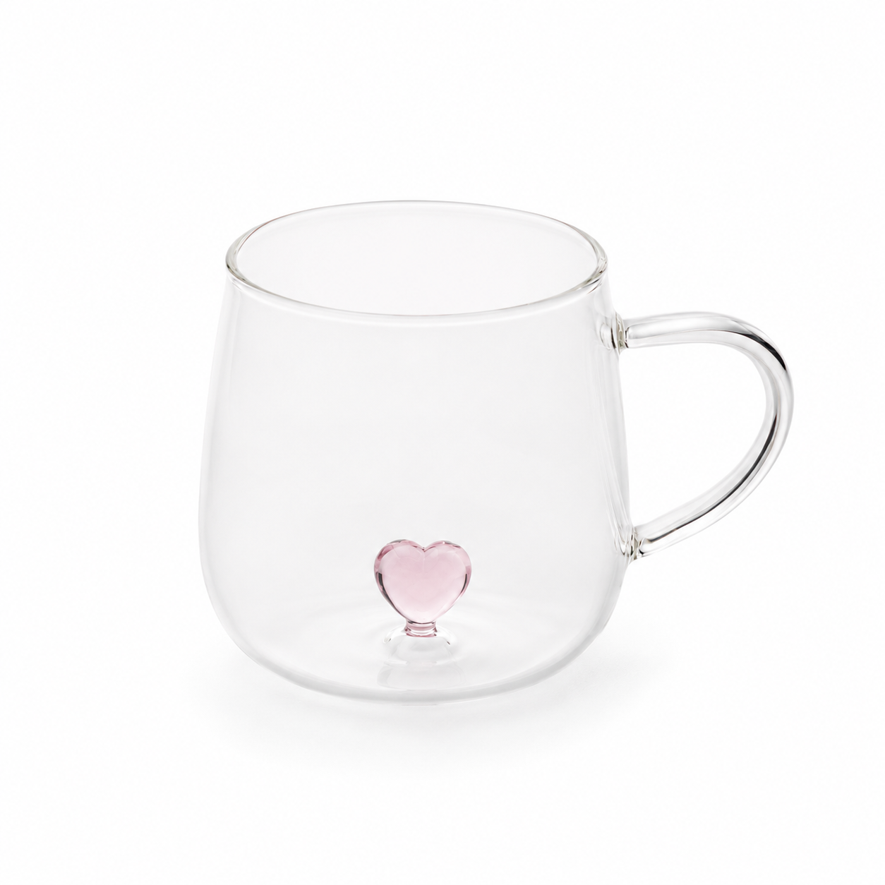 Прозрачна стъклена чаша с деликатно розово сърце в основата и минималистичен дизайн върху бял фон.